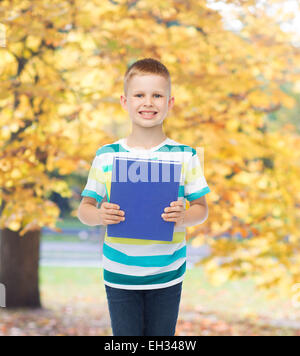 Poco sorridente studente Ragazzo con libro blu Foto Stock