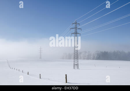 Giornata invernale linea elettrica ad alta tensione coperti con trasformata per forte gradiente frost piccola foresta in background Foto Stock