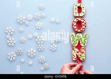 Vista aerea del decorate biscotti di Natale l'ortografia in giù su sfondo blu con i fiocchi di neve Foto Stock