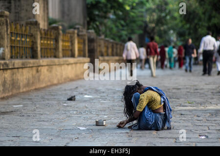 Una giovane ragazza nasconde il suo volto mentre è seduto e a mendicare per le strade di Mumbai, India. Foto Stock