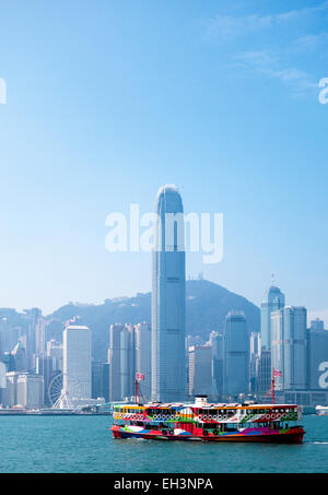 Un traghetto nel porto di Hong Kong con lo skyline della città in background Foto Stock