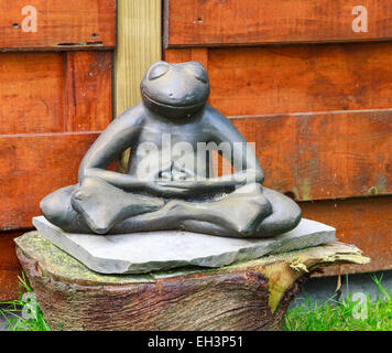 Il giardino di pietra a forma di rana la meditazione seduta su un tronco di albero Foto Stock