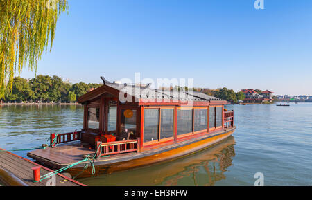 Cinese tradizionale in legno rosso acqua taxi stand barca ormeggiata sul Lago Ovest e costa. Famoso Parco in Hangzhou city centre, Cina Foto Stock