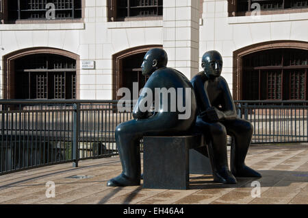 Scultura di due figure su un banco di lavoro rivolti in direzioni opposte. Foto Stock