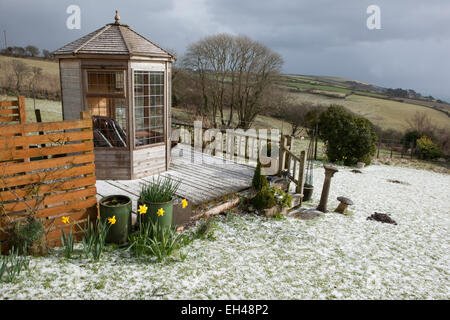 Meteo insolita per il mese di marzo in Cornovaglia, una caduta di neve copre il prato e la decking intorno alla casa estiva. Foto Stock