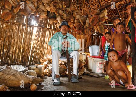 Panama, San Blas arcipelago, Kuna Yala, Kune comunità indigena, ritratto di un capo nativo Kuna stava seduto in casa sua, circondato dai suoi figli e nipoti Foto Stock