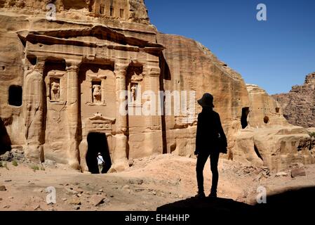 Giordania, Nabataean sito archeologico di Petra, elencato come patrimonio mondiale dall UNESCO, silhouette di donna guardando la facciata del soldato romano della tomba scavata una roccia arenaria faccia Foto Stock