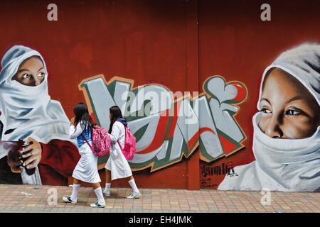 Ecuador, Imbabura, Atuntaqui, ecuadoriana ragazze della scuola di fronte a un muro di graffiti raffiguranti una donna velata Foto Stock