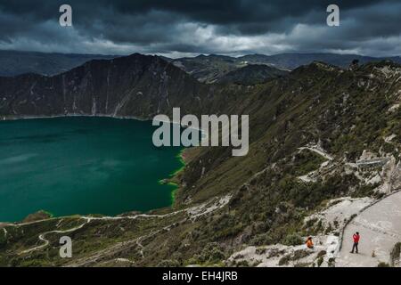 Ecuador, Cotopaxi, Lago di Quilotoa, vista panoramica di turisti fotografare su una laguna nel cratere di un vulcano estinto, sotto un cielo tempestoso Foto Stock