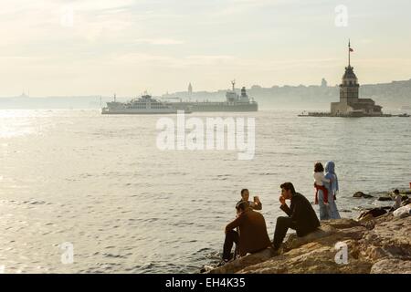 Turchia, Istanbul, Uskudar distretto, famiglia turco godendo il tardo pomeriggio di luce sulle rocce sul bordo del Bosforo Foto Stock