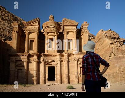 Giordania, Nabataean sito archeologico di Petra, elencato come patrimonio mondiale dall UNESCO, silhouette di donna guardando il famoso e riccamente intagliati facciata di Al Deir (monastero), scolpito in una roccia arenaria faccia Foto Stock