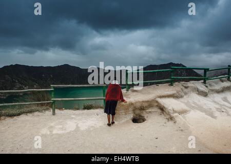 Ecuador, Cotopaxi, Lago di Quilotoa, donna ecuadoriana, guardando da un promontorio, una laguna nel cratere di un vulcano estinto Foto Stock