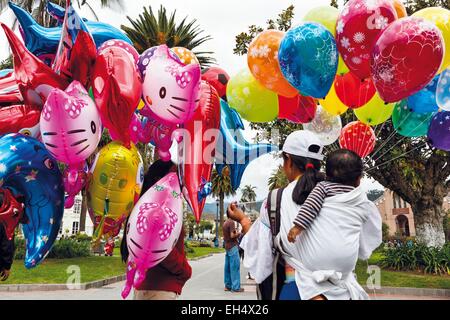 Ecuador, Imbabura, Otavalo, scene di strada nel centro della città nei giorni di mercato di Otavalo, commessa di palloncini per bambini in primo piano Foto Stock