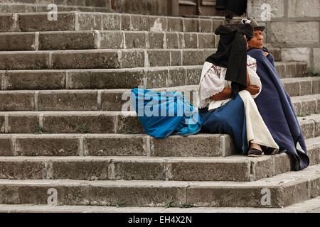 Ecuador, Imbabura, Cotacaxi, Intyrami giorno, giovane anziani seduti sui gradini della chiesa, durante le feste Foto Stock