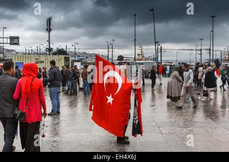 Turchia, Istanbul, centro storico sono classificati come patrimonio mondiale dall' UNESCO, quartiere Eminonu, bandiere turche venditore su una pubblica piazza nel centro di passanti, un giorno nuvoloso Foto Stock