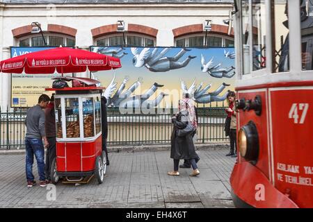 Turchia, Istanbul, Beyoglu, quartiere Taksim, Piazza Taksim, il tram che passa da un restauro tradizionale cariole su un marciapiede Foto Stock