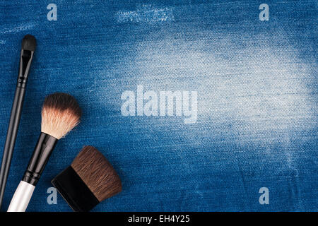 Tre pennelli per il trucco giacente sul jeans blu, con posto per il testo Foto Stock