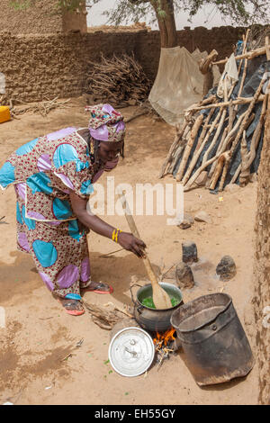 Le donne del gruppo giardino, Tera, a ovest del Niger: Ramata Hama, 38, preparazione di foglie di meringa ha appena scelto per la sua famiglia del pasto. Foto Stock