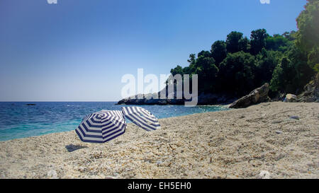 Due ombrelloni sulla spiaggia. Due ombrelloni su una bellissima spiaggia selvaggia in Grecia Foto Stock