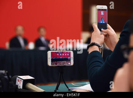 (150307) -- PECHINO, 7 marzo 2015 (Xinhua) -- Un giornalista utilizza un telefono cellulare e un mini treppiede per girare dei video durante un panel di discussione dei deputati per la Cina del XII congresso nazionale del popolo (ANP) da est della Cina di Provincia di Shandong a Pechino Capitale della Cina, 7 marzo 2015. (Xinhua/Wang Jianhua) (yxb) Foto Stock