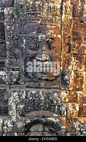 La luce del sole splende attraverso uno dei tanti volti di pietra scolpite nella roccia al Bayon, parte del tempio di Angkor complesso in western Cam Foto Stock