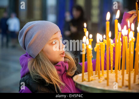 Poco bionda ragazza caucasica con candele in ortodossi Chiesa Russa Foto Stock