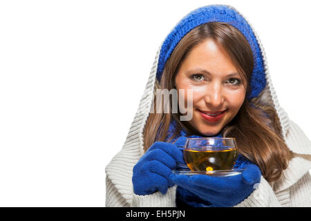 Moda giovane donna in una maglia blu inverno ensemble e cruscotto collo jersey sorseggiando una tazza di tè caldo con un sorriso in uno sforzo per mantenere in caldo, isolato su bianco Foto Stock