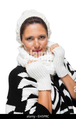 Attraente donna elegante in inverno fashion snuggling in giù nel suo bianco sciarpa e in bianco e nero ponticello per scongiurare il freddo w Foto Stock