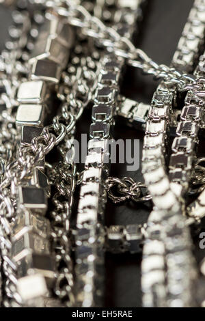 Pila assortiti di catene in argento con scatola di lucido catene, catene di cubo e ordinario di catena collegati su sfondo grigio concettuale del f Foto Stock