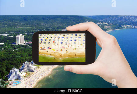 Concetto di viaggio - turistica prendendo foto di Albena spiaggia di sabbia sul cellulare gadget, Bulgaria Foto Stock