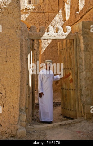 L uomo nella porta del vecchio edificio mudbrick, Al-Hamra, Oman Foto Stock