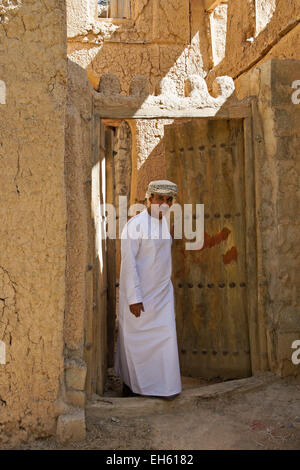 L uomo nella porta del vecchio edificio mudbrick, Al-Hamra, Oman Foto Stock