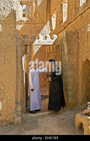 Gli uomini nella porta del vecchio edificio mudbrick, Al-Hamra, Oman Foto Stock