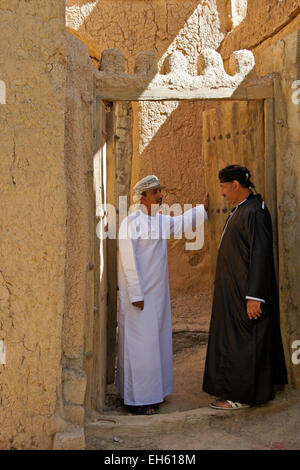 Gli uomini nella porta del vecchio edificio mudbrick, Al-Hamra, Oman Foto Stock