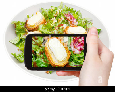 Fotografare il concetto di cibo - turistica prendendo foto di insalata verde con formaggio di capra su gadget mobile, Italia Foto Stock