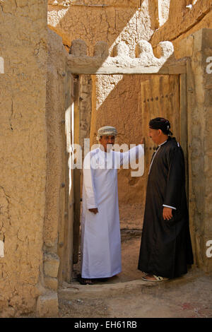 Gli uomini nella porta del vecchio edificio mudbrick, Al-Hamra, Oman Foto Stock