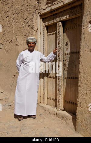 L uomo nella porta del vecchio edificio mudbrick, Al-Hamra, Oman Foto Stock