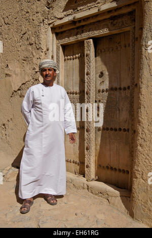 L uomo nella porta del vecchio edificio mudbrick, Al-Hamra, Oman Foto Stock