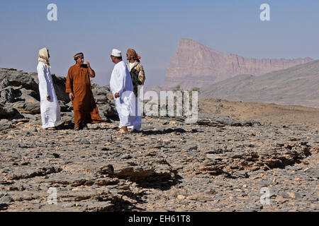 Omani uomini parlare, Jebel Misht in background, Oman Foto Stock