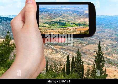 Concetto di viaggio - turistica prendendo foto della Terra Santa dal Monte Nebo in Giordania su gadget mobile Foto Stock