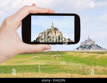 Concetto di viaggio - tourist prendere le foto di mont saint Michel abbey, Normandia, Francia sul gadget mobile Foto Stock