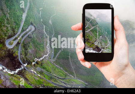 Concetto di viaggio - turistica prendendo foto di Trollstigen (troll) percorso serpeggiante strada di montagna in Norvegia su gadget mobile Foto Stock