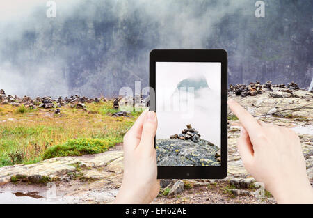 Concetto di viaggio - turistica prendendo foto della piramide di pietra sulla montagna altopiano in Norvegia su gadget mobile Foto Stock