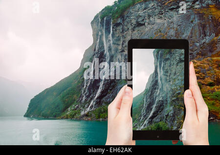 Concetto di viaggio - turistica prendendo foto di sette sorelle cascata di oltre il Geirangerfjord sul gadget mobile Foto Stock