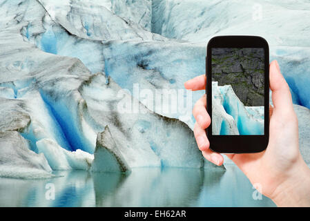 Concetto di viaggio - turistica prendendo foto di neve che si scioglie nel ghiacciaio briksdal in Norvegia su gadget mobile Foto Stock
