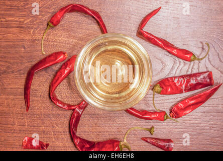 Chilis secco che circonda una ciotola di vetro con olio Foto Stock