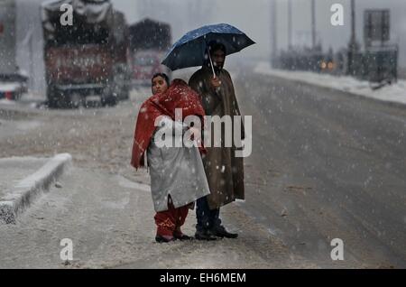 Srinagar, Indiano-controllato del Kashmir. 8 Mar, 2015. Una famiglia del Kashmir attende per bus sulla periferia di Srinagar, capitale estiva di Indiano-Kashmir controllata, 8 marzo 2015. Indiano-Kashmir controllata ricevuto forti piogge e nevicate di domenica, costringendo la chiusura di Srinagar-Jammu autostrada nazionale, l'unica strada di collegamento tra la regione del Kashmir in India. © Javed Dar/Xinhua/Alamy Live News Foto Stock