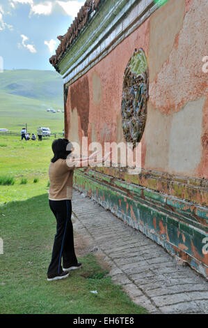 Monastero di Amarbayasgalant, tempo di Festival, Lady in preghiera davanti al muro del monastero Foto Stock