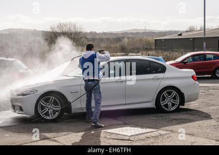 Un uomo lava le vetture con una rondella di potenza in corrispondenza di un "Euro" L autolavaggio Foto Stock