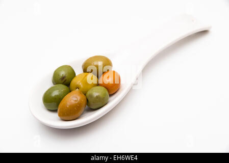 Le olive in un cucchiaio su sfondo bianco Foto Stock